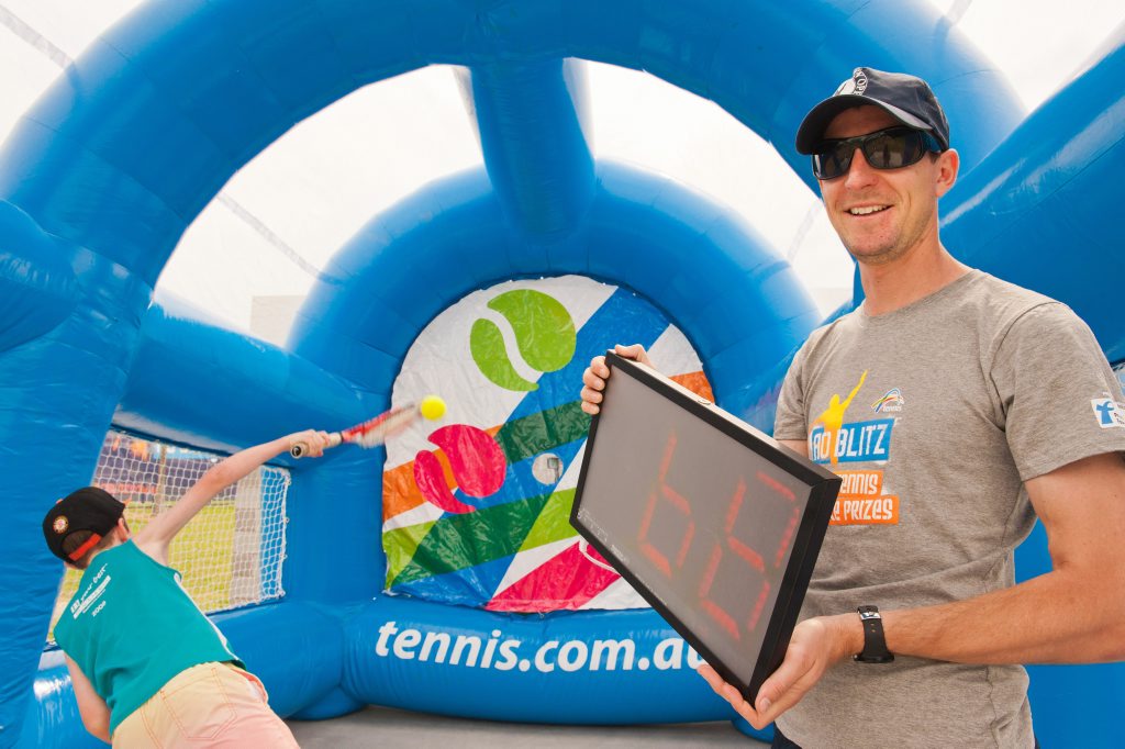 The Australian Open Blitz at the Harbour Tennis Academy, Westside Tennis Courts, Coffs Harbour: Harry McMillan serves up while Matt Starr from Tennis NSW checks the speed. Photo: Rob Wright / The Coffs Coast Advocate