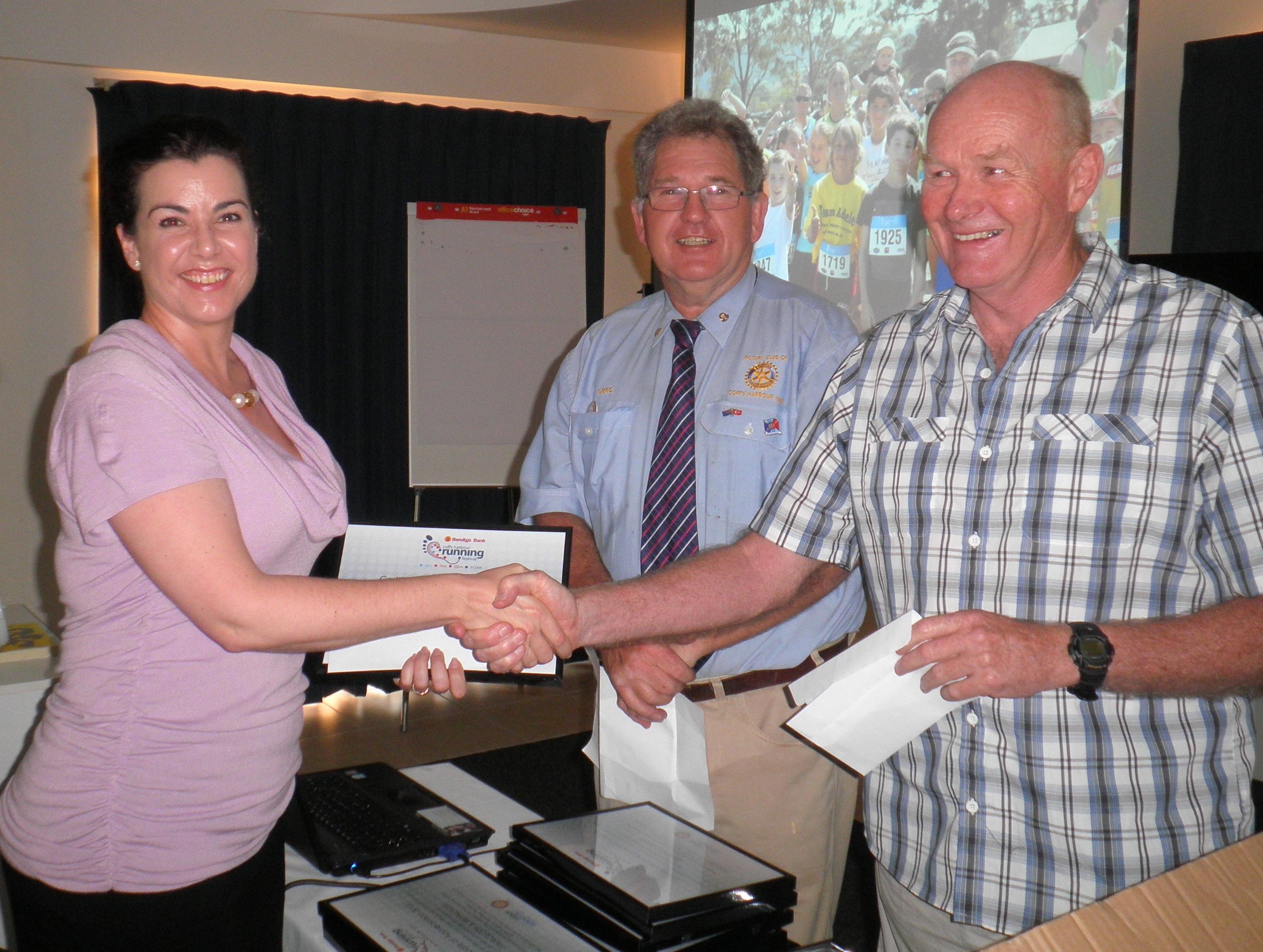 Camp Quality's Sonja Wallis receives a financial boost from rotarian Greg Joyce and running festival co-promoter Mick Maley