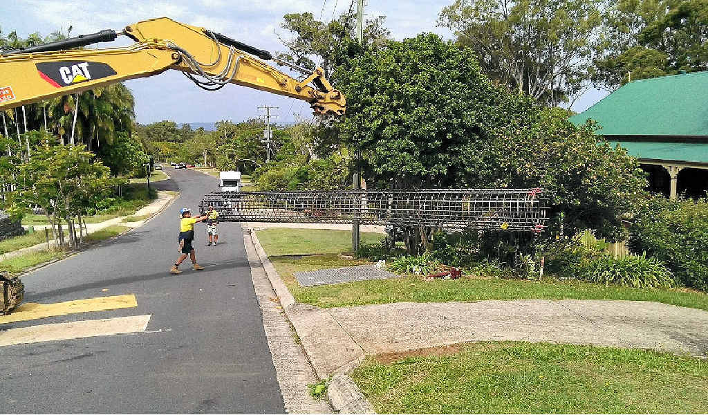 RED-FACED: Workers remove the cage which rolled down from a construction site and took out a letterbox. RED-FACED: Workers remove the cage which rolled down from a construction site and took out a letterbox.
