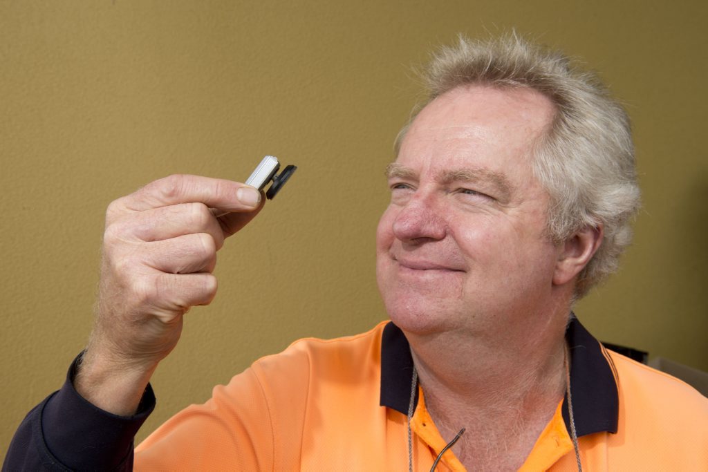 Les Butler takes a look at his new hearing device, which stays in place with magnets. Les Butler takes a look at his new hearing device, which stays in place with magnets.