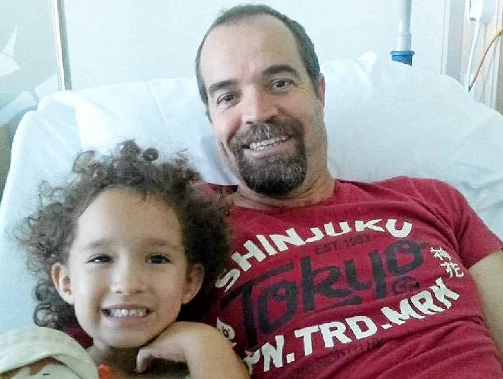 BRAVE FACE: Damien Holt with his three-year-old daughter, Gemma, in his hospital bed in Brisbane. BRAVE FACE: Damien Holt with his three-year-old daughter, Gemma, in his hospital bed in Brisbane.