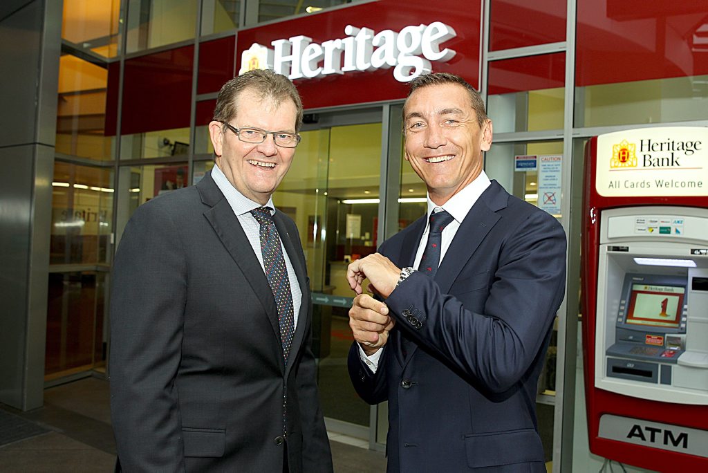 Queensland sporting legend Mat Rogers (right) models the M.J. Bale suit embedded with a contactless payment chip, along with Heritage Bank chief operating officer John Williams. Photo Contributed Queensland sporting legend Mat Rogers (right) models the M.J. Bale suit embedded with a contactless payment chip, along with Heritage Bank chief operating officer John Williams. Photo Contributed
