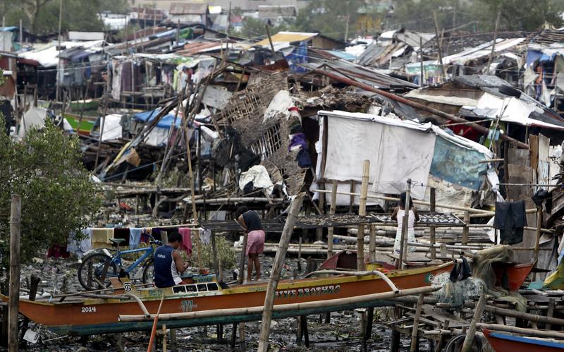 Filipinos clear debris outside their damaged houses after strong winds and rain brought by Typhoon Rammasun at a fishing village in Paranaque city, South of Manila, Philippines, 19 July 2014. Filipinos clear debris outside their damaged houses after strong winds and rain brought by Typhoon Rammasun at a fishing village in Paranaque city, South of Manila, Philippines, 19 July 2014.
