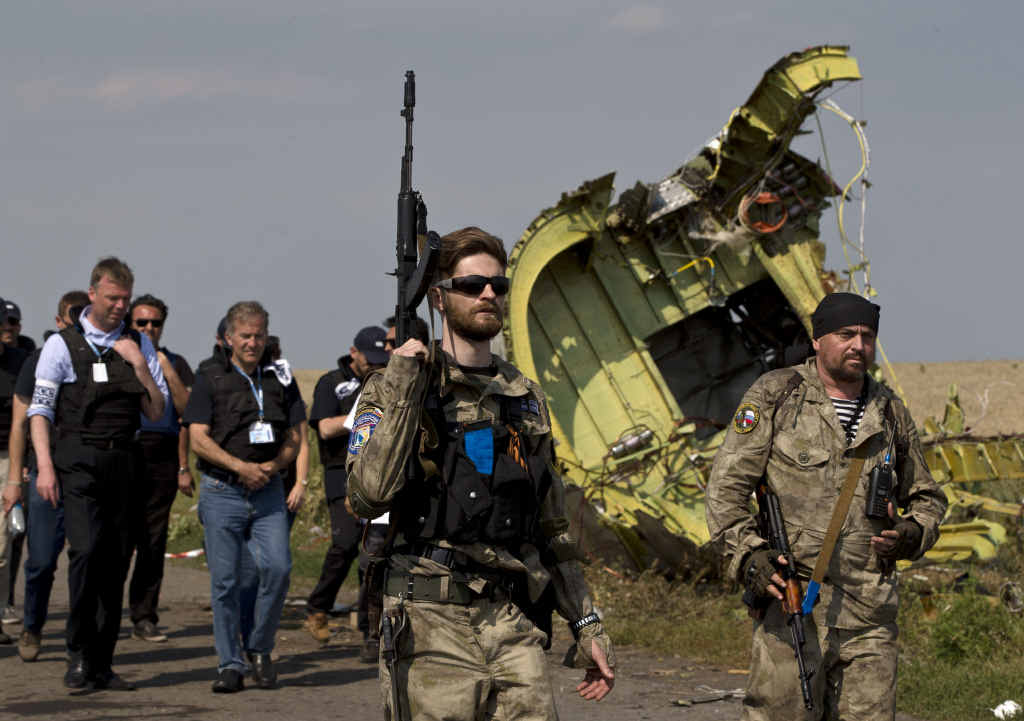 Pro-Russian rebels, with guns, pass plane wreckage. Pro-Russian rebels, with guns, pass plane wreckage.