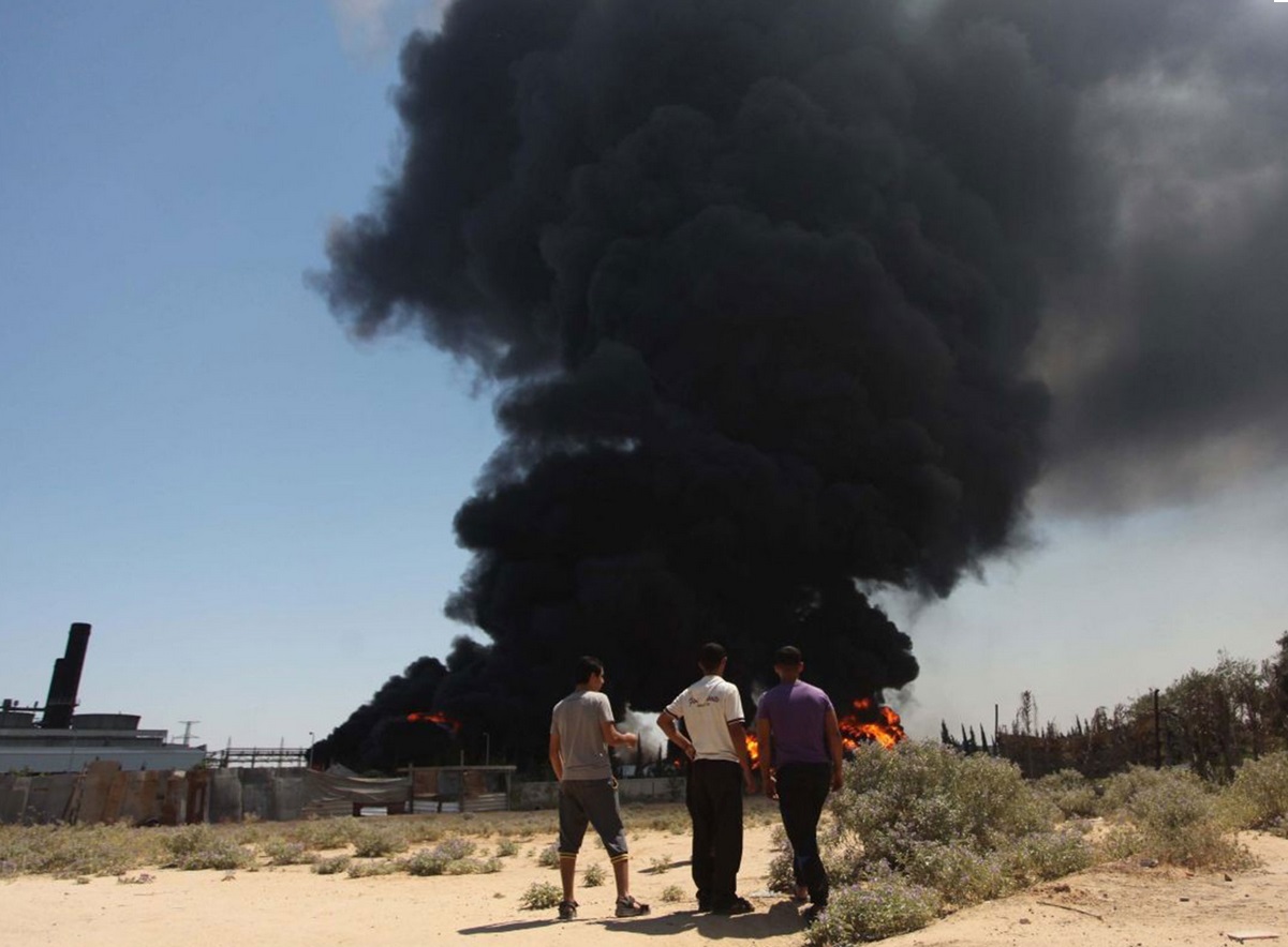 Thick black smoke rises from the burning fuel tank of a power plant in Gaza region, after it was struck by two tank shells Thick black smoke rises from the burning fuel tank of a power plant in Gaza region, after it was struck by two tank shells