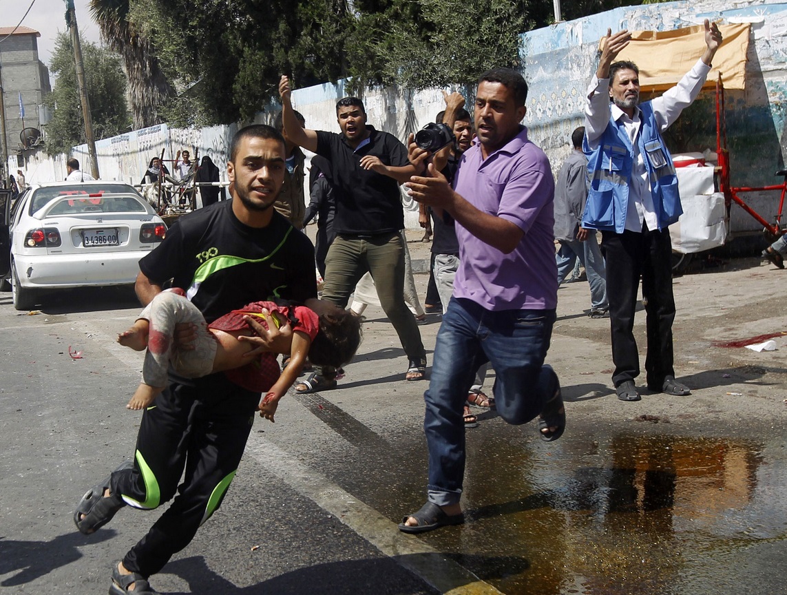 A Palestinian man carries an injured child following the Israeli military strike on the UN shelter in Rafah. At least 10 people were killed in the strike, the seventh on a UN-run shelter in Gaza A Palestinian man carries an injured child following the Israeli military strike on the UN shelter in Rafah. At least 10 people were killed in the strike, the seventh on a UN-run shelter in Gaza