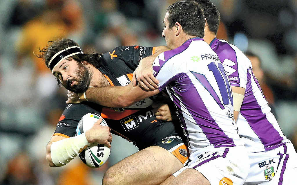 Aaron Woods of the Tigers is tackled by Bryan Norrie of the Storm at Campbelltown Sports Stadium in Sydney last night. Aaron Woods of the Tigers is tackled by Bryan Norrie of the Storm at Campbelltown Sports Stadium in Sydney last night.