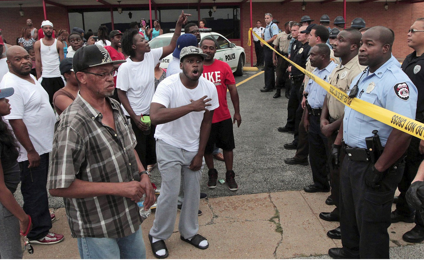 Ferguson police officers try to calm down a crowd near the scene where 18-year-old Michael Brown was fatally shot by police Ferguson police officers try to calm down a crowd near the scene where 18-year-old Michael Brown was fatally shot by police