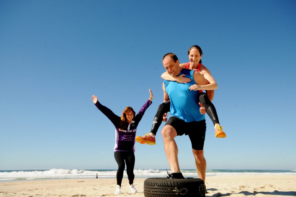 TACKLING OBASTACLES: Yonit Kittay (left) from The Cancer Council cheers on North Coast Radiology team member Paul Morris while he piggyback's his colleague Kim Churchill in training for a fundraising obstacle course to be held in Ballina on September 17 as part of the Ballina Relay for Life. TACKLING OBASTACLES: Yonit Kittay (left) from The Cancer Council cheers on North Coast Radiology team member Paul Morris while he piggyback's his colleague Kim Churchill in training for a fundraising obstacle course to be held in Ballina on September 17 as part of the Ballina Relay for Life.