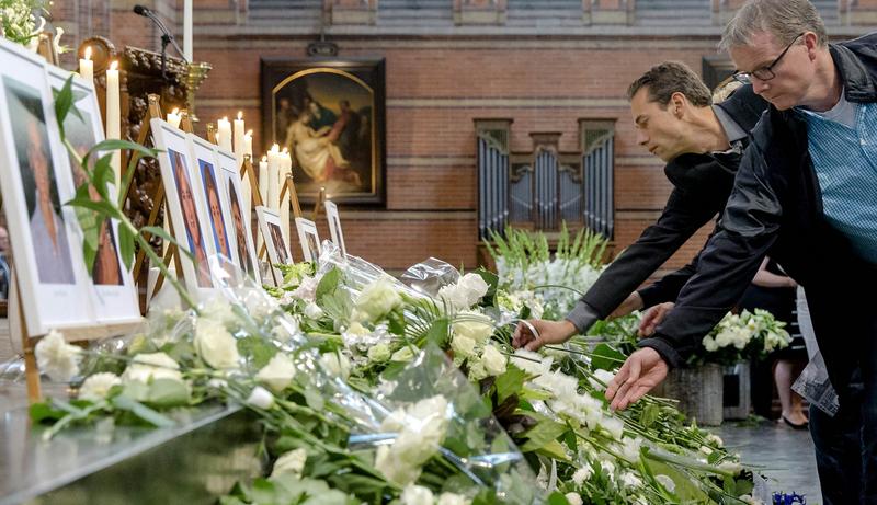 People place flowers under near photographs of victims during a memorial service in the Sint-Vitus church in Hilversum on August 17, 2014. People place flowers under near photographs of victims during a memorial service in the Sint-Vitus church in Hilversum on August 17, 2014.