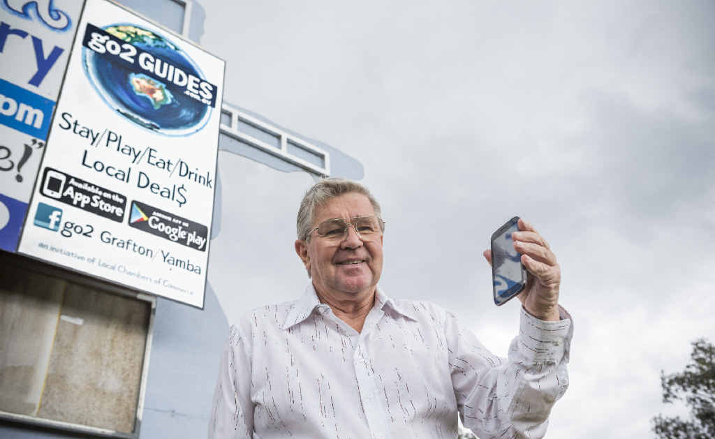 APPY MAN: President of the Maclean Chamber of Commerce John Riggall looks at the Go2Guide app in front of signage for it on the Pacific Hwy. Photo: Adam Hourigan APPY MAN: President of the Maclean Chamber of Commerce John Riggall looks at the Go2Guide app in front of signage for it on the Pacific Hwy. Photo: Adam Hourigan