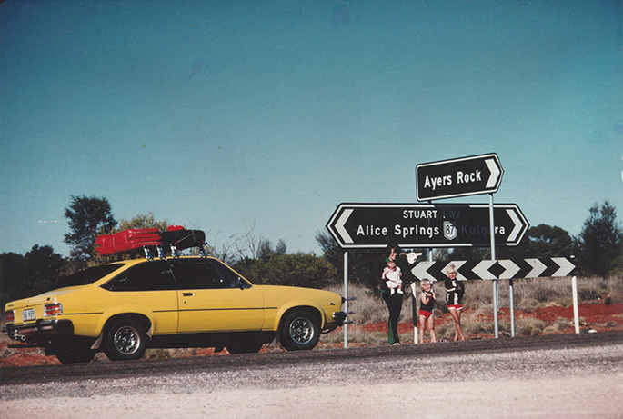 Lindy Chamberlain holding Azaria Chamberlain, with Aidan and Reagan Chamberlain, standing on Stuart Highway with sign to 'Ayers Rock', alongside their Torana, 16 August, 1980. Lindy Chamberlain holding Azaria Chamberlain, with Aidan and Reagan Chamberlain, standing on Stuart Highway with sign to 'Ayers Rock', alongside their Torana, 16 August, 1980.