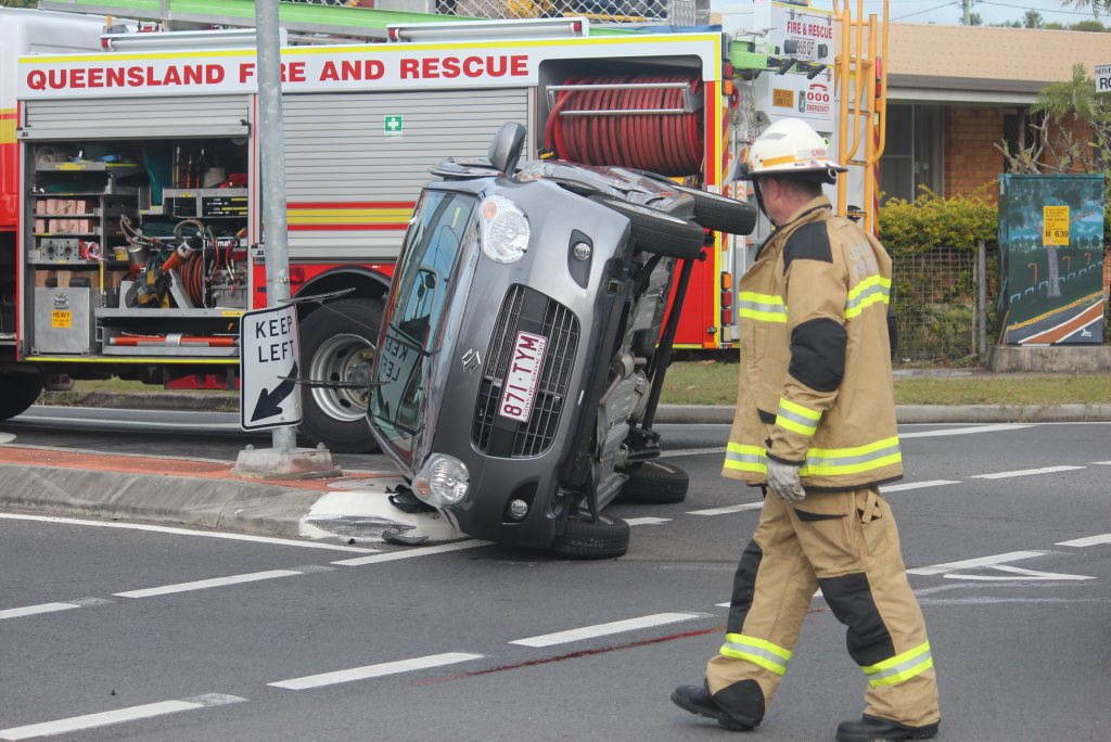 A firefighter walks around a car on its side after a crash on the corner of Robert St and Boat Harbour Dr in Urangan. A firefighter walks around a car on its side after a crash on the corner of Robert St and Boat Harbour Dr in Urangan.