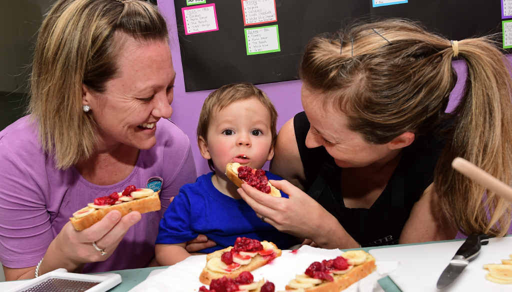 BERRY NICE: Cassandra Fenaughty (right) and Goodstart Early Learning Centre director Tash Sullivan tempt toddler Beauden May. BERRY NICE: Cassandra Fenaughty (right) and Goodstart Early Learning Centre director Tash Sullivan tempt toddler Beauden May.