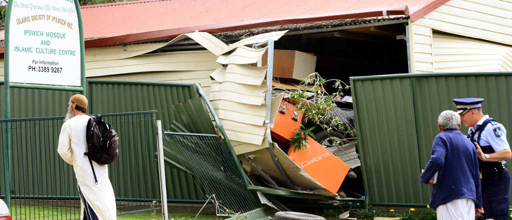 HOW BIZARRE: Inspector Keith McDonald (far right) speaks to a resident after a car crashed into a garage next to the Islamic Society of Ipswich. HOW BIZARRE: Inspector Keith McDonald (far right) speaks to a resident after a car crashed into a garage next to the Islamic Society of Ipswich.