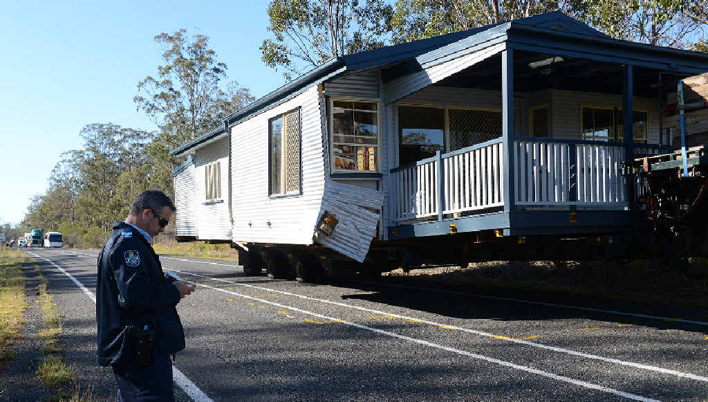 HOUSE CRASH: A police officer checks the scene of a crash on the Bruce Hwy where a car hit a truck. HOUSE CRASH: A police officer checks the scene of a crash on the Bruce Hwy where a car hit a truck.