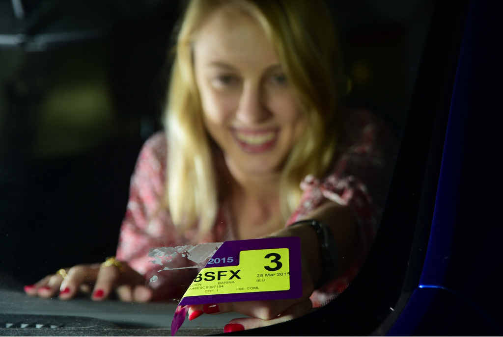Leilani Waters peels off her car registration sticker, which from today is no longer required. Leilani Waters peels off her car registration sticker, which from today is no longer required.