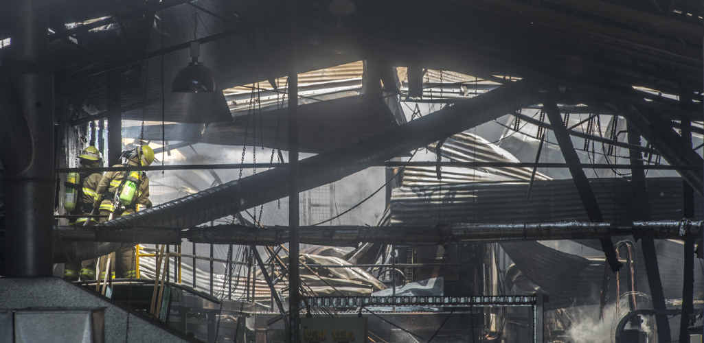 Firefighters pick their way through the fire-damaged shed at Big River Timbers. Firefighters pick their way through the fire-damaged shed at Big River Timbers.