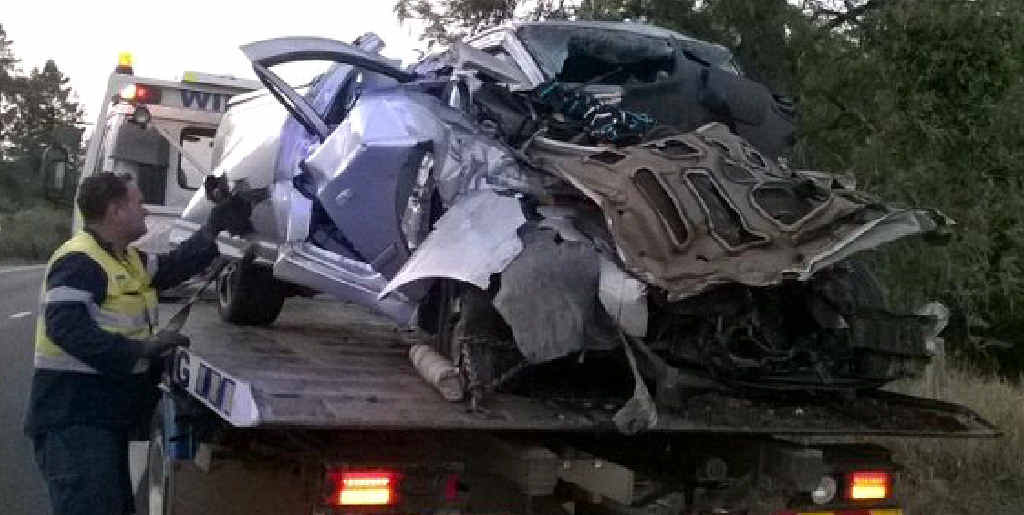 HUGE IMPACT: A tow truck driver operator gets ready to tow the Falcon ute from the crash site Sunday morning. HUGE IMPACT: A tow truck driver operator gets ready to tow the Falcon ute from the crash site Sunday morning.