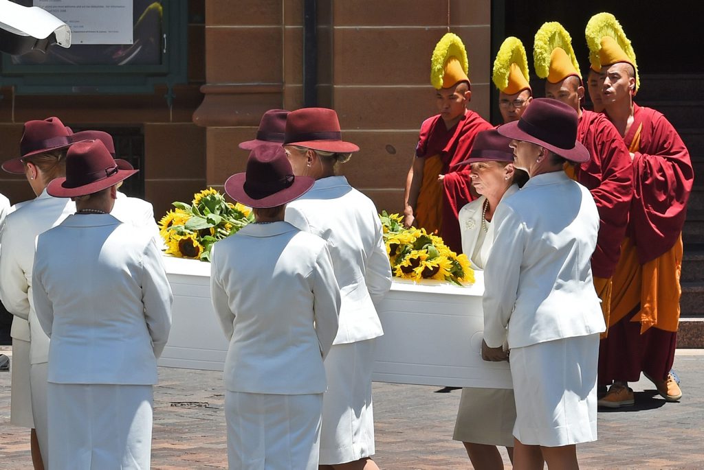 Buddhist monks pray as the coffin of Sydney siege victim Tori Johnson is placed in a hearse after a funeral service in Sydney. Buddhist monks pray as the coffin of Sydney siege victim Tori Johnson is placed in a hearse after a funeral service in Sydney.