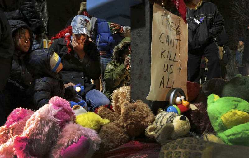 Courtney Palmer, center left, a cousin of Antonio Martin, mourns the loss at a growing memorial in a gas station parking lot in Berkeley, Mo., Wednesday, Dec. 24, 2014. Courtney Palmer, center left, a cousin of Antonio Martin, mourns the loss at a growing memorial in a gas station parking lot in Berkeley, Mo., Wednesday, Dec. 24, 2014.