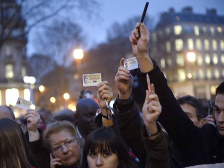 Journalists raise their press cards as others hold up pens during a vigil at the Place de la Republique Journalists raise their press cards as others hold up pens during a vigil at the Place de la Republique