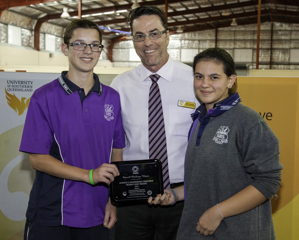 USQ executive manager Brett Langabeer presents Aldridge State High School, represented by William Slade and Lindsey Massey, with the 2014 regional trophy. USQ executive manager Brett Langabeer presents Aldridge State High School, represented by William Slade and Lindsey Massey, with the 2014 regional trophy.