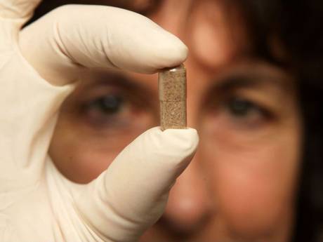 A woman holds up a dried-placenta capsule. The product was last year caught up in new GM food rules A woman holds up a dried-placenta capsule. The product was last year caught up in new GM food rules