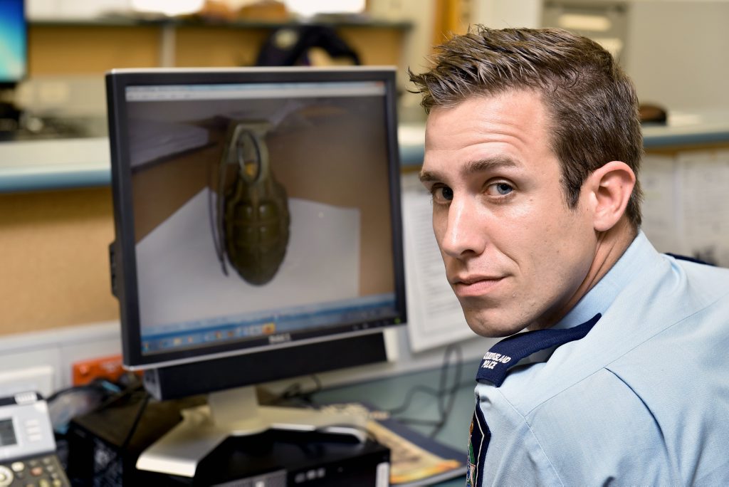Constable Jordan Powell with a picture of the live grenade surrendered at the Hervey Bay police station. Constable Jordan Powell with a picture of the live grenade surrendered at the Hervey Bay police station.