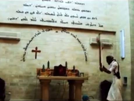 An Isis militant smashes a cross on an altar An Isis militant smashes a cross on an altar