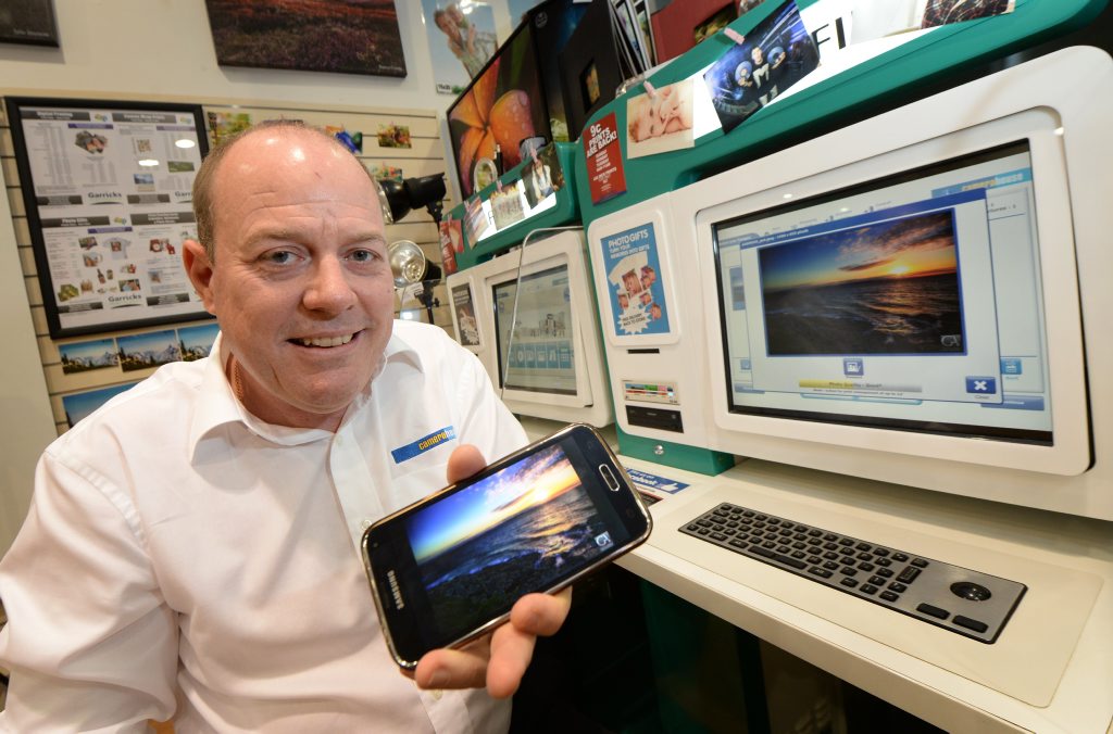 Long time store manager Dale Winters has bought the Camera House in Stockland Shopping Centre and has a number of innovations he plans to introduce in coming months including the abilty to wirelessly transfer photos from your smart phone to the photo kiosk for printing. Photo: Chris Ison / The Morning Bulletin Long time store manager Dale Winters has bought the Camera House in Stockland Shopping Centre and has a number of innovations he plans to introduce in coming months including the abilty to wirelessly transfer photos from your smart phone to the photo kiosk for printing. Photo: Chris Ison / The Morning Bulletin