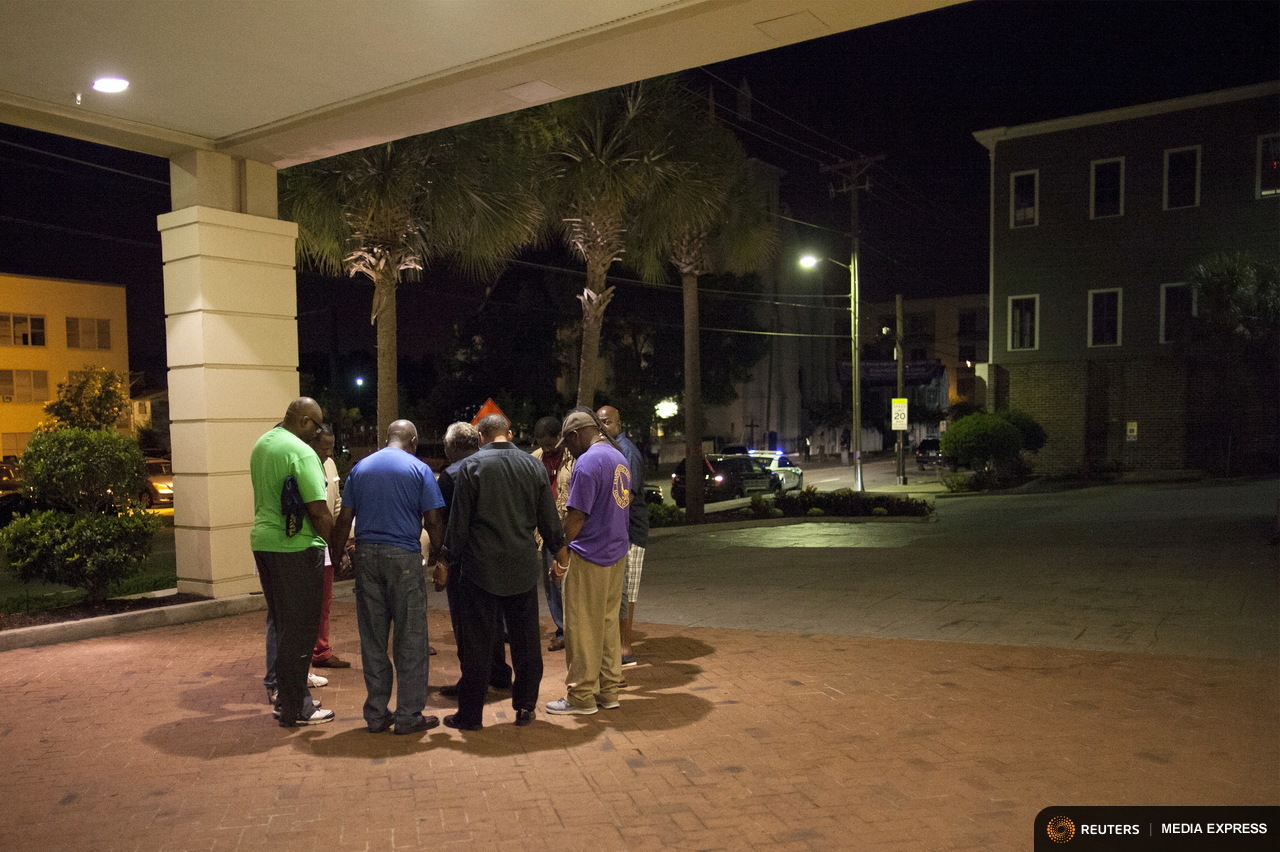 A small prayer circle forms nearby where police are responding to a shooting at the Emanuel AME Church in Charleston, South Carolina. A small prayer circle forms nearby where police are responding to a shooting at the Emanuel AME Church in Charleston, South Carolina.