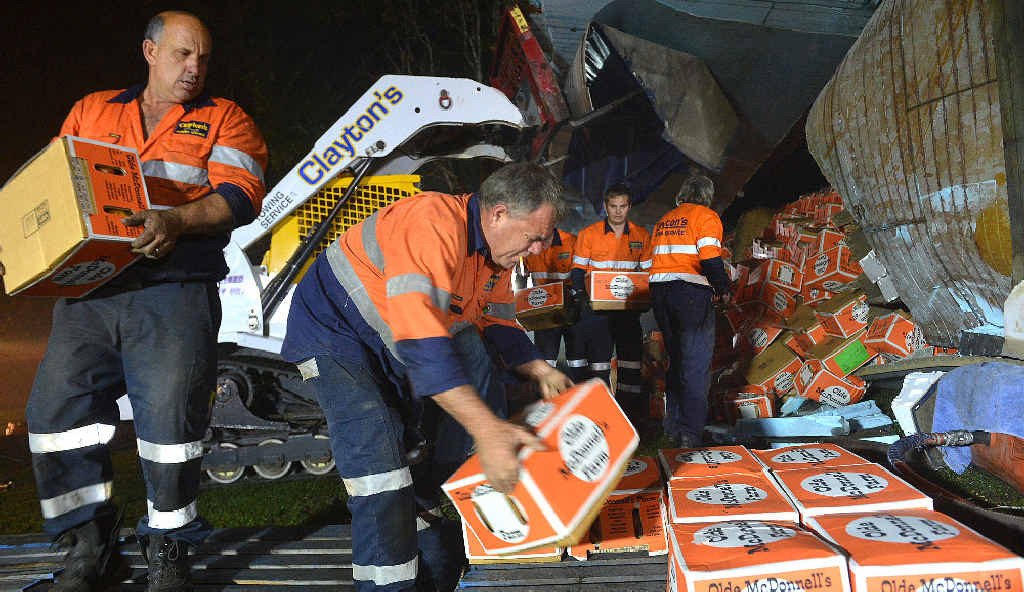 SALVAGE: Claytons Towing workers stack apparently undamaged boxes of produce at the crash scene. SALVAGE: Claytons Towing workers stack apparently undamaged boxes of produce at the crash scene.