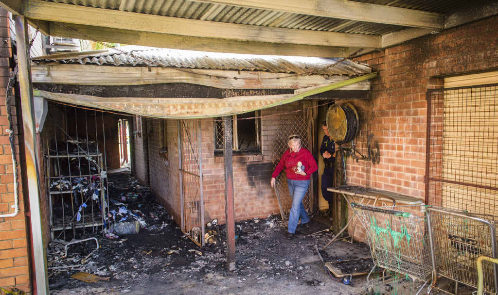 EXTENSIVE DAMAGE: An Anglican Op Shop volunteer is escorted by police through the scene of the fire at the shop. EXTENSIVE DAMAGE: An Anglican Op Shop volunteer is escorted by police through the scene of the fire at the shop.