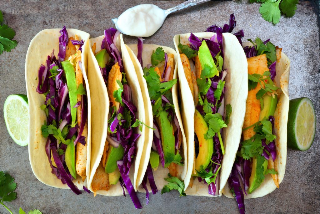 Fish tacos with red cabbage lime slaw on rustic tray Fish tacos with red cabbage lime slaw on rustic tray