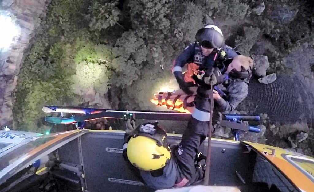 ALMOST THERE: An RACQ Capricorn Rescue crewman reaches the chopper with the injured hiker high above the rugged Blackdown Tableland terrain.