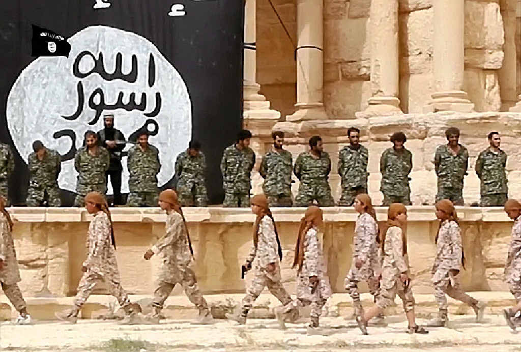GRUESOME VIOLENCE: These grabs from an IS propaganda video allegedly show 25 Syrian government soldiers on their knees in the ancient amphitheatre in Palmyra awaiting their execution. It appears the soldiers were executed by children or teenagers. GRUESOME VIOLENCE: These grabs from an IS propaganda video allegedly show 25 Syrian government soldiers on their knees in the ancient amphitheatre in Palmyra awaiting their execution. It appears the soldiers were executed by children or teenagers.