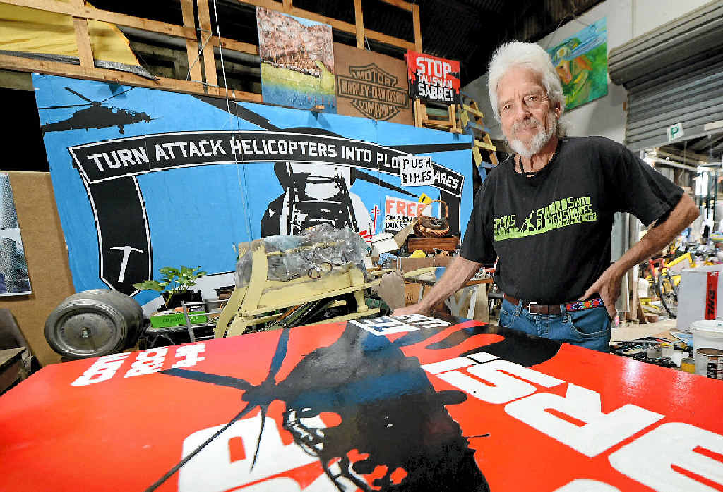 Peace activist Graeme Dunstan puts the finishing touches to the mural which was mounted on the side of the Peacebus used in anti-Talisman Sabre protests.