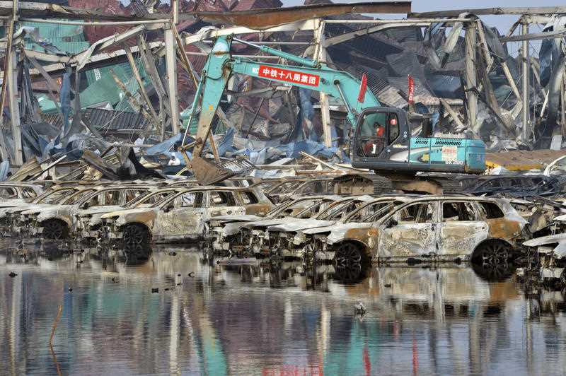 Chinese workers in protective suits began clearing wreckage on Thursday, including charred car bodies and crumpled shipping containers, from the site of a chemical warehouse that exploded last week. Chinese workers in protective suits began clearing wreckage on Thursday, including charred car bodies and crumpled shipping containers, from the site of a chemical warehouse that exploded last week.