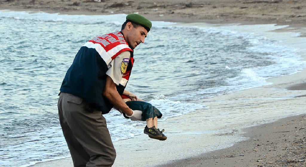A Turkish police officer carries a young boy who drowned in a failed attempt to sail to the Greek island of Kos. A Turkish police officer carries a young boy who drowned in a failed attempt to sail to the Greek island of Kos.