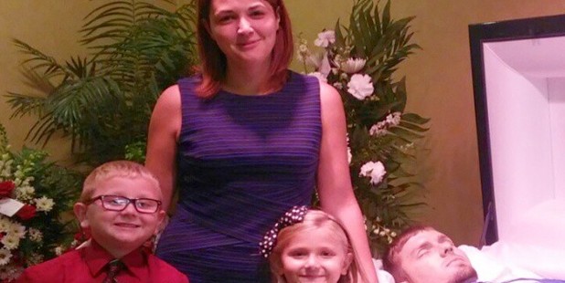 Eva Holland poses with her children, Lucas and Ava, before the casket of her husband, Mike Settles, 26, who died of a recent heroin overdose. Photo / Facebook Eva Holland poses with her children, Lucas and Ava, before the casket of her husband, Mike Settles, 26, who died of a recent heroin overdose. Photo / Facebook