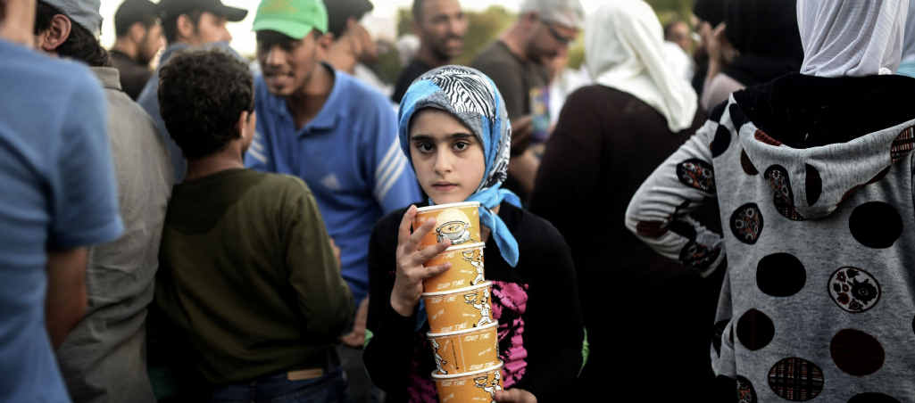 IN NEED: A girl carries cartons of soup as Syrian refugees queue for food as they rest beside the highway on their way to the border between Turkey and Greece. IN NEED: A girl carries cartons of soup as Syrian refugees queue for food as they rest beside the highway on their way to the border between Turkey and Greece.