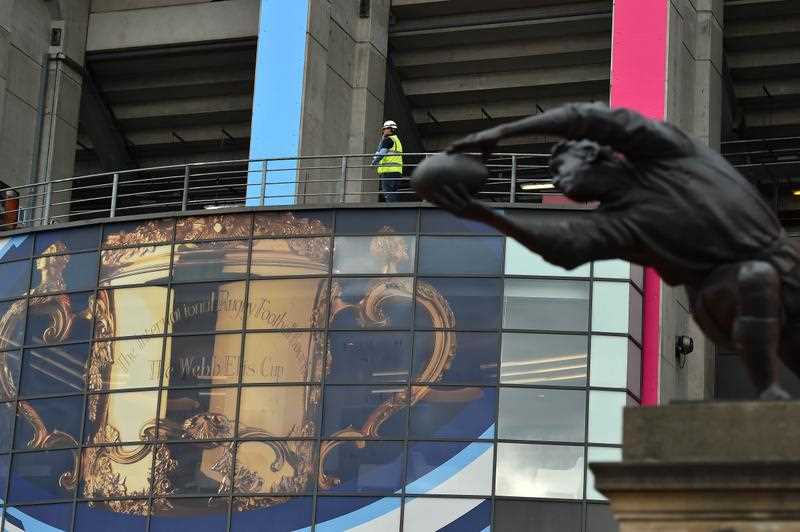 A worker walks by a giant billboard of the Web Ellis Cup, the trophy of the Rugby World Cup, displayed at the Twickenham Stadium, West of London on September 15, 2015. Twickenham Stadium will host the opening match England vs Fiji next September 18, 2015. A worker walks by a giant billboard of the Web Ellis Cup, the trophy of the Rugby World Cup, displayed at the Twickenham Stadium, West of London on September 15, 2015. Twickenham Stadium will host the opening match England vs Fiji next September 18, 2015.