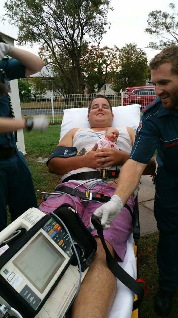 Rhett McLeod is collected by paramedics after being hit by lightning in his Koongal home. His four-year-old daughter Mylee gave him her doll to take to hospital with him. Rhett McLeod is collected by paramedics after being hit by lightning in his Koongal home. His four-year-old daughter Mylee gave him her doll to take to hospital with him.