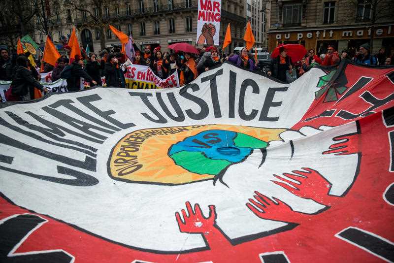 A giant sign reading Climate justice is seen among thousands demanding climate justice and environment protection in Paris on December 12, 2015. A climate march was organized by several NGOs as COP21 negotiations come to an end. A giant sign reading Climate justice is seen among thousands demanding climate justice and environment protection in Paris on December 12, 2015. A climate march was organized by several NGOs as COP21 negotiations come to an end.