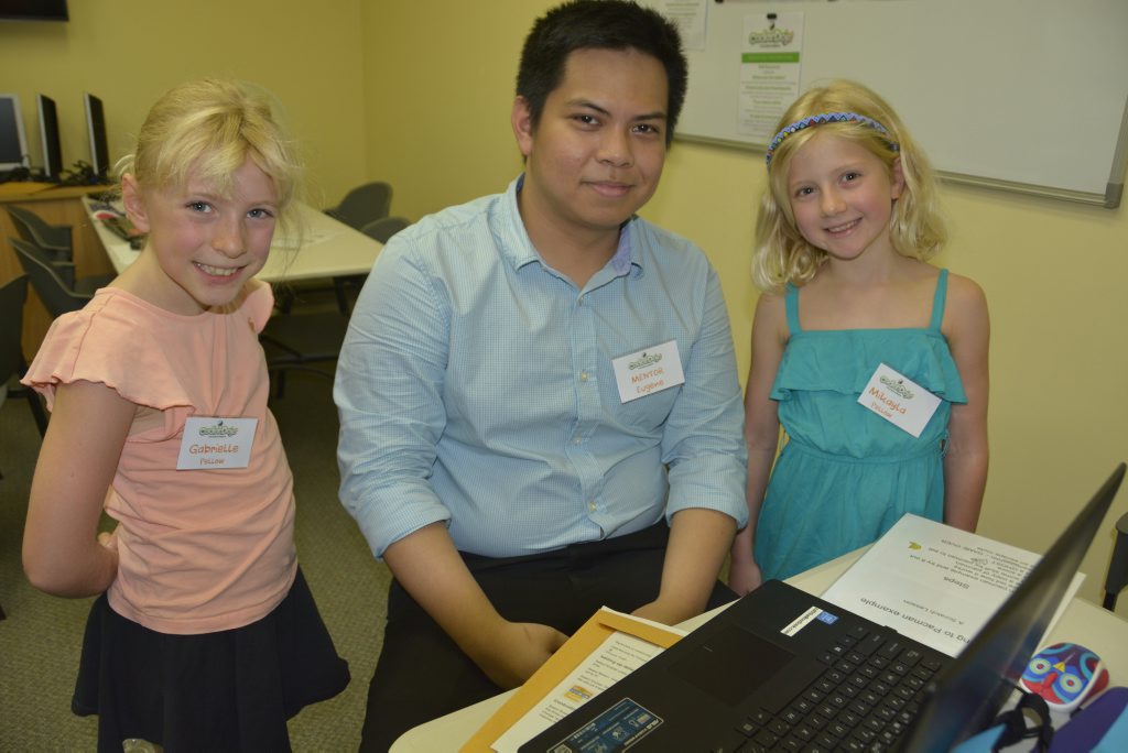 Gabrielle Pellow (from left) watches as mentor Eugene Correa shows her and sister Mikayla coding at the CoderDojo Toowoomba classes run through Canvas Coworking.