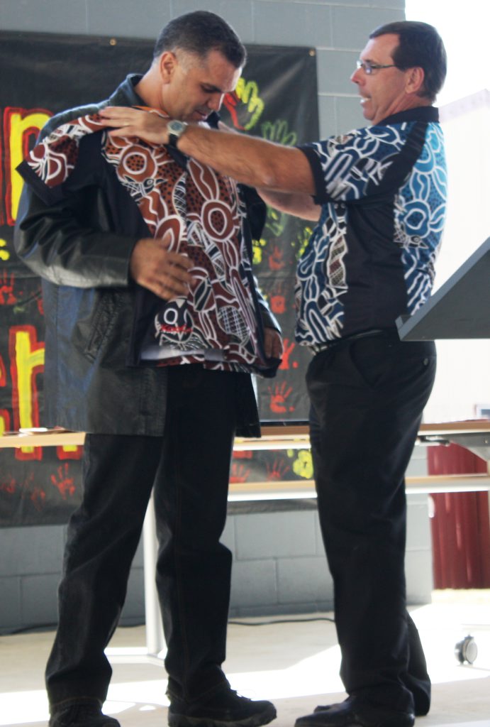 Former principal Chris Sarra being presented with a Cherbourg State School staff shirt by principal Peter Sansby. Former principal Chris Sarra being presented with a Cherbourg State School staff shirt by principal Peter Sansby.