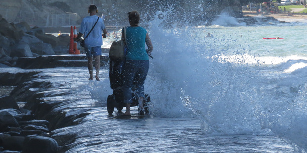 The woman tries to navigate her way along the rocks at Mairangi Bay as the waves crash into her. Photo / Eliane Souza
The woman tries to navigate her way along the rocks at Mairangi Bay as the waves crash into her. Photo / Eliane Souza