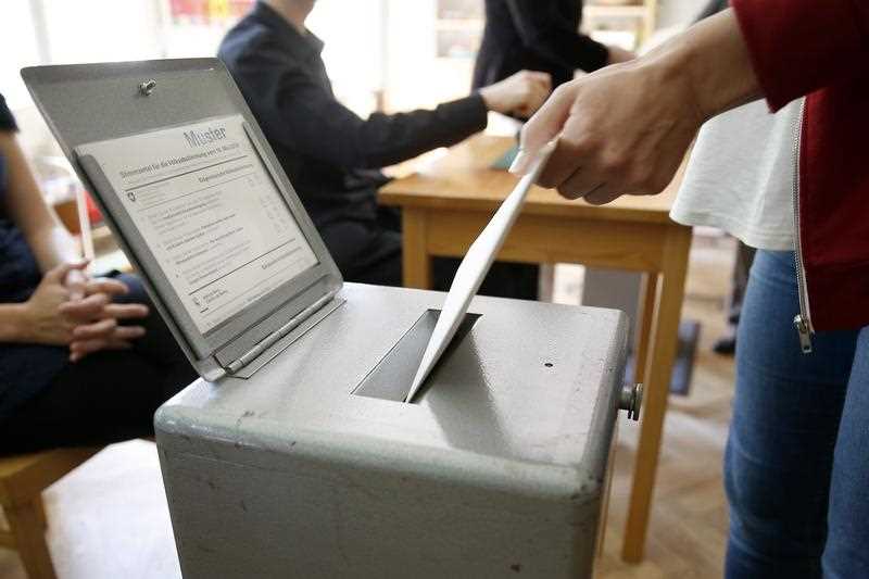 A voter drops in his ballot in an election office in Bern, Switzerland A voter drops in his ballot in an election office in Bern, Switzerland