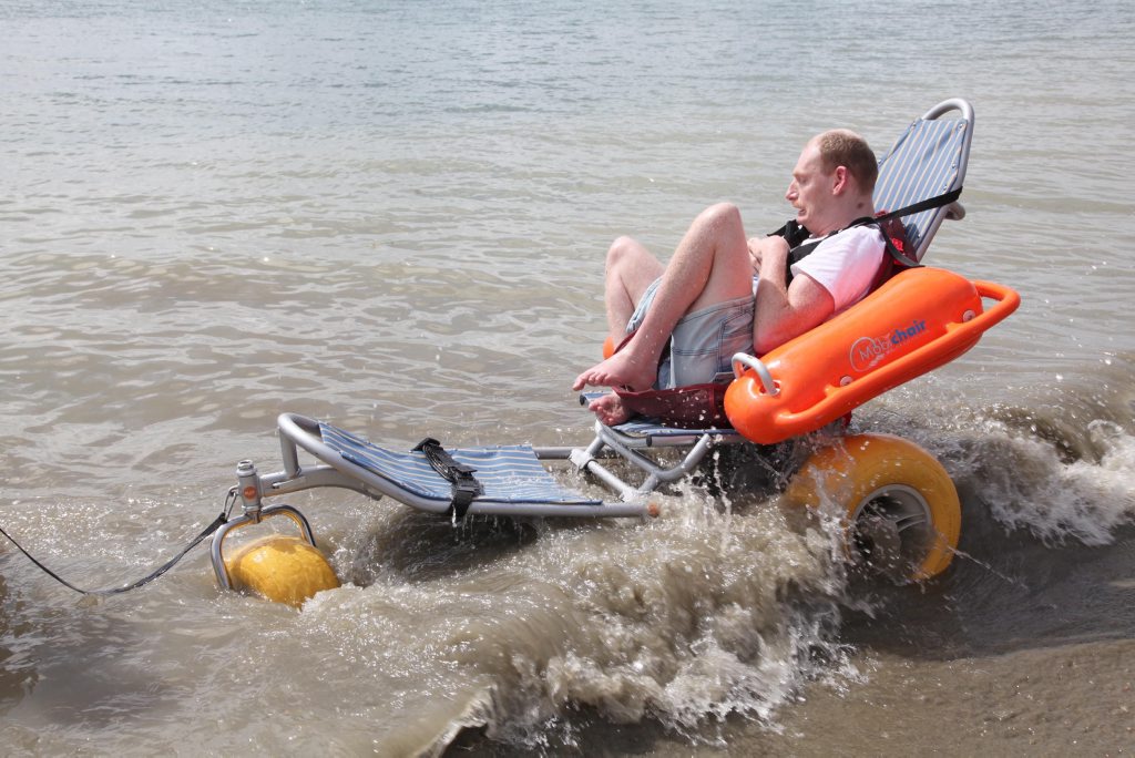 Tony Summerville touches sea water for the first time on Sunday morning, having used a Mobi-Mat to access the beach. Photo: Jocelyn Watts / Fraser Coast Chronicle Tony Summerville touches sea water for the first time on Sunday morning, having used a Mobi-Mat to access the beach. Photo: Jocelyn Watts / Fraser Coast Chronicle